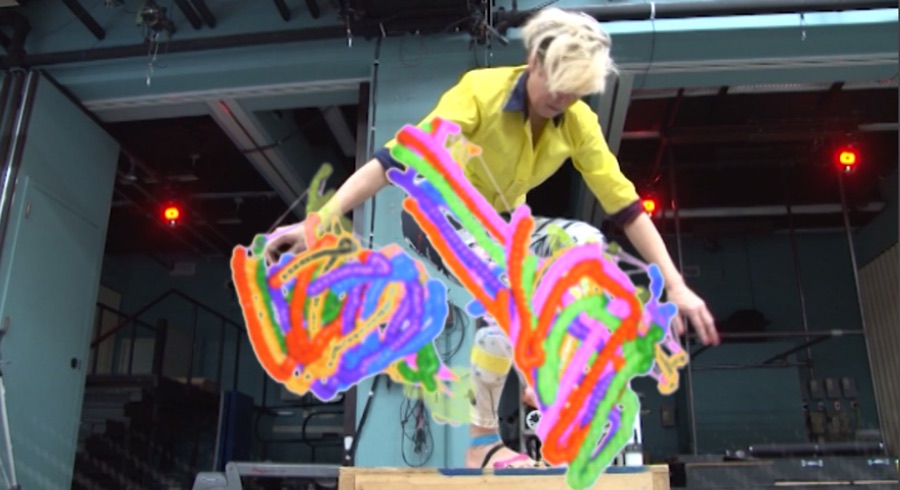 A performer’s movements rendered as vivid colored motion trails.
